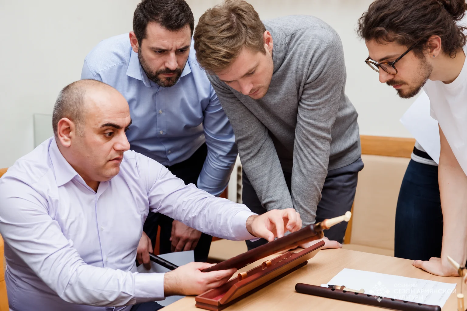 Participants gather around a teacher to look at an instrument
